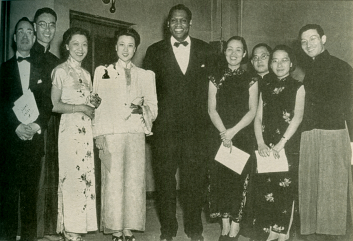 Black and white photo of people dressed in formal attire in a row at a banquet.