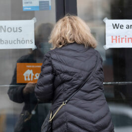 A customer entering a restaurant with help wanted signs.