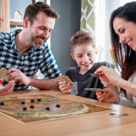 A father, son and mother play a board game.