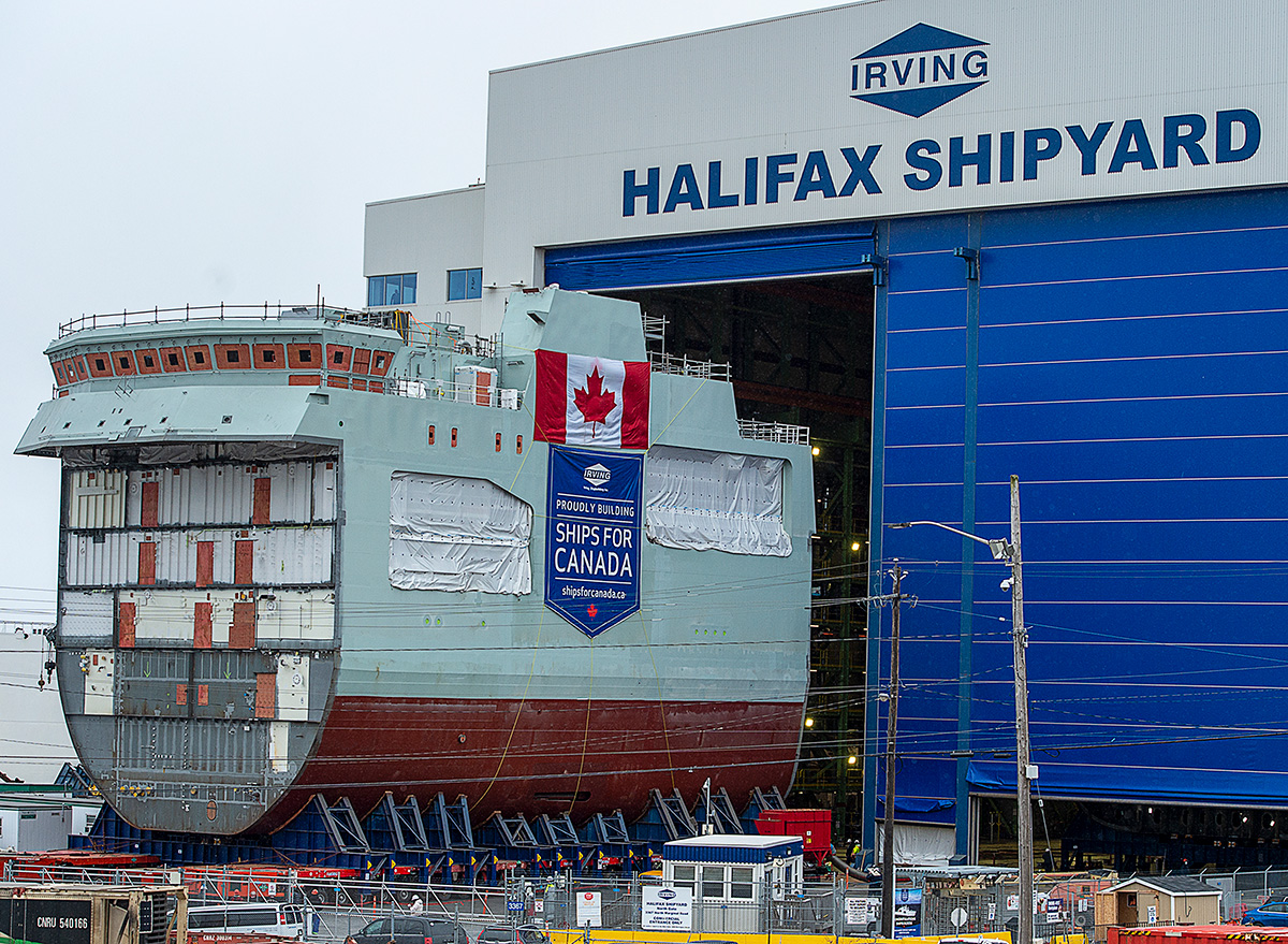 The centre block of a future patrol ship is seen outside a shipbuilding facility that says Halifax shipyard.