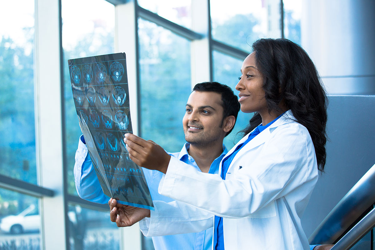 A woman and a man in white coats looking at medical images.