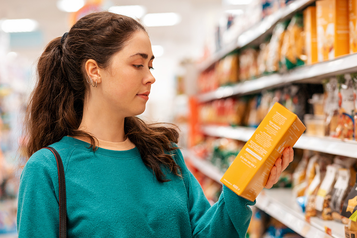 Woman reading the nutritional label of a grocery store product.