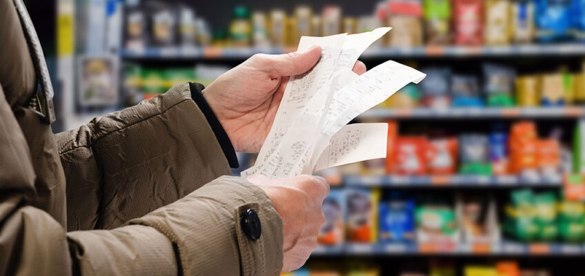 A man looking at a receipt in a grocery store.