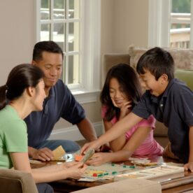A family sits down to board game.