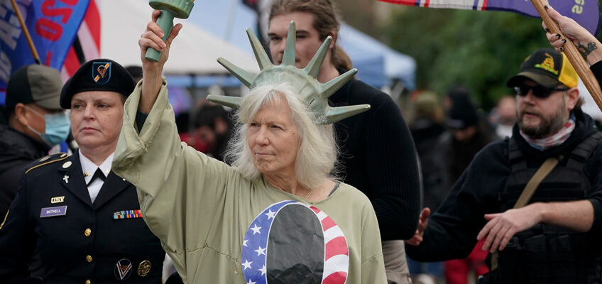 a woman dresses as the statue of liberty wearing a tshirt with the letter q on it.