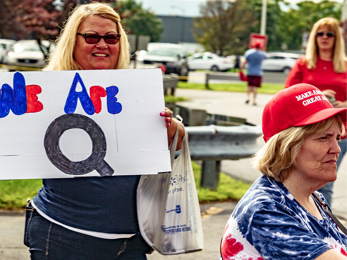 a woman holds a WE ARE Q sign