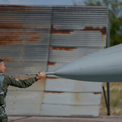 A soldier touches the nose of his fighter jet.