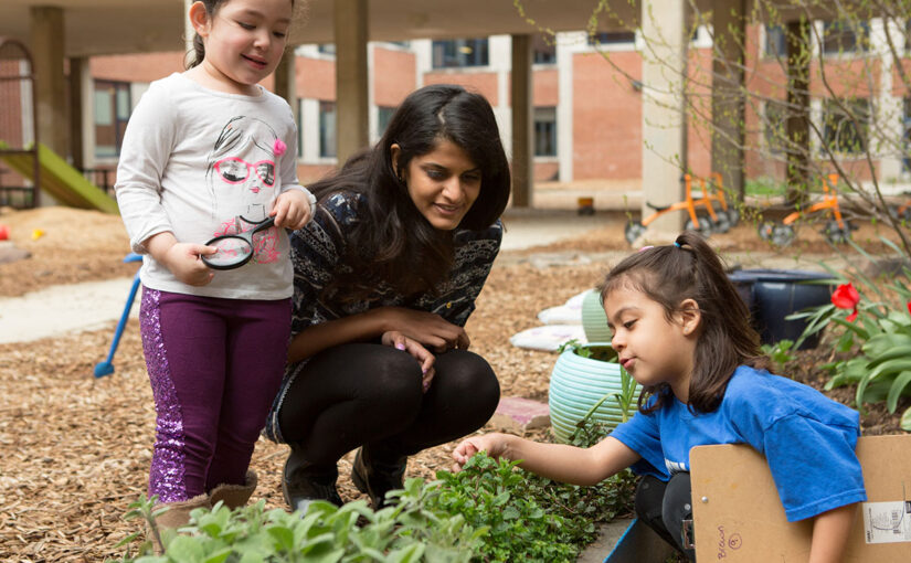 An educator seen in garden with children.