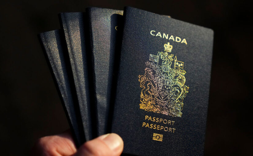 A hand holding four Canadian passports.