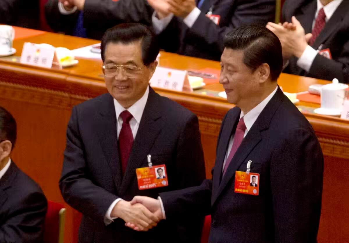 Hu Jintao, left, shakes hands with his successor Xi Jinping. Both men wear dark suits, white shirts and red ties.