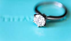 A diamond engagement ring on a Tiffany blue background.