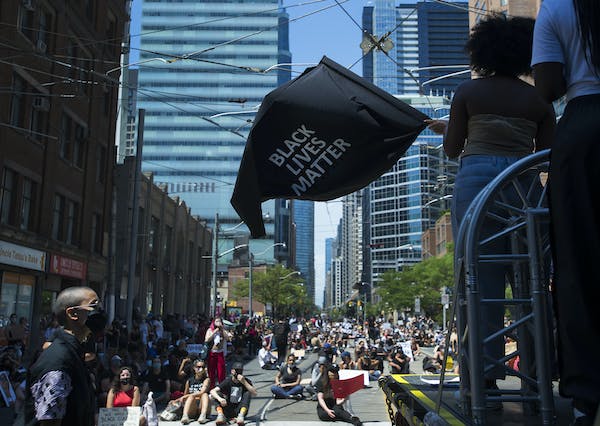 A woman waves a black lives matter flag on a downtown Toronto street
