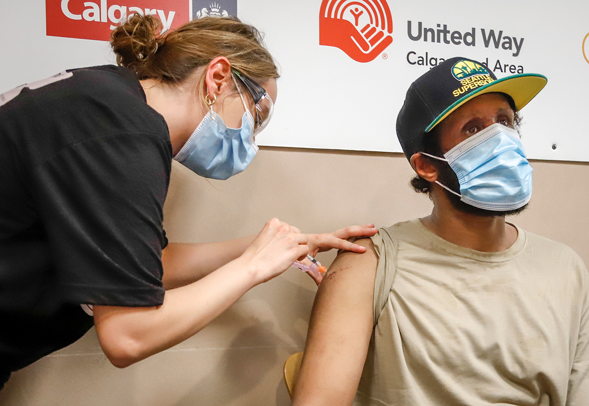 Nurse giving a man a vaccination shot in the arm.