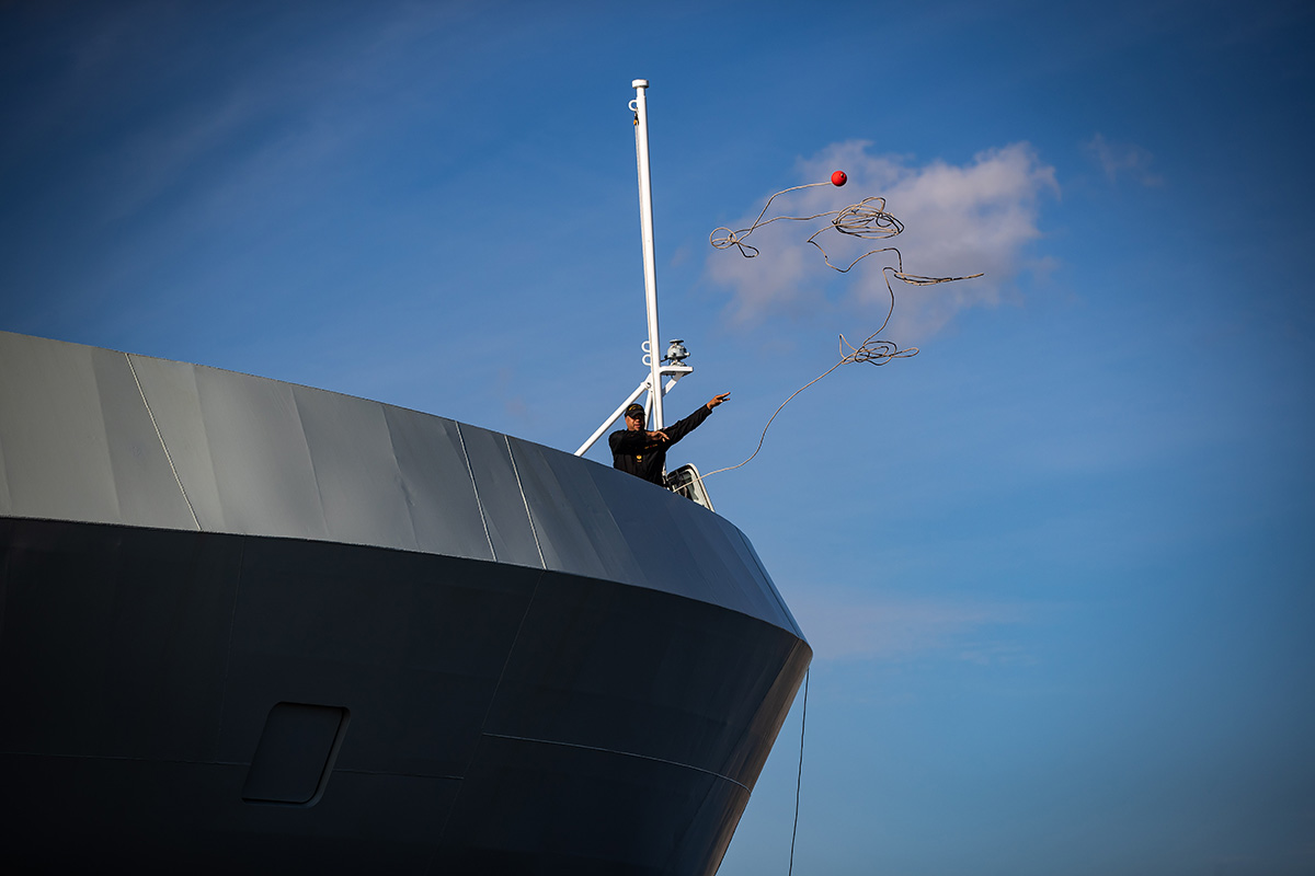A crew member tosses a line from a patrol ship.