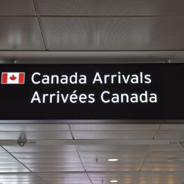 A sign that reads: Canada arrivals with a Canadian flag.