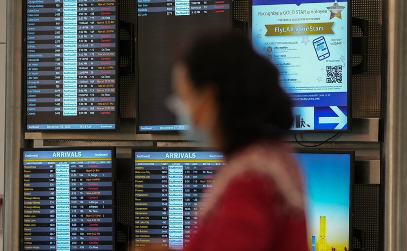 Cancelled flights are seen in red on a digital flight schedules display behind the blurry image of a woman.