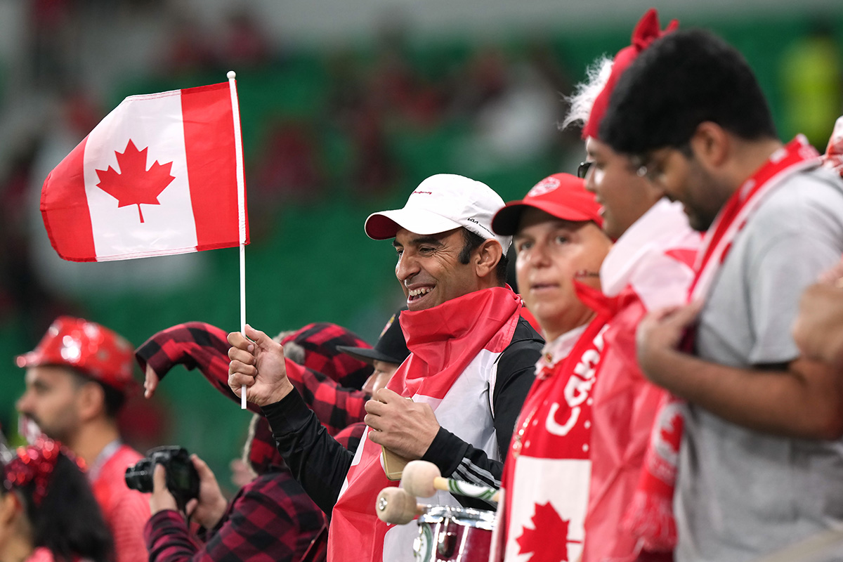 A group of football fans one of whom is waving a Canadian flag.
