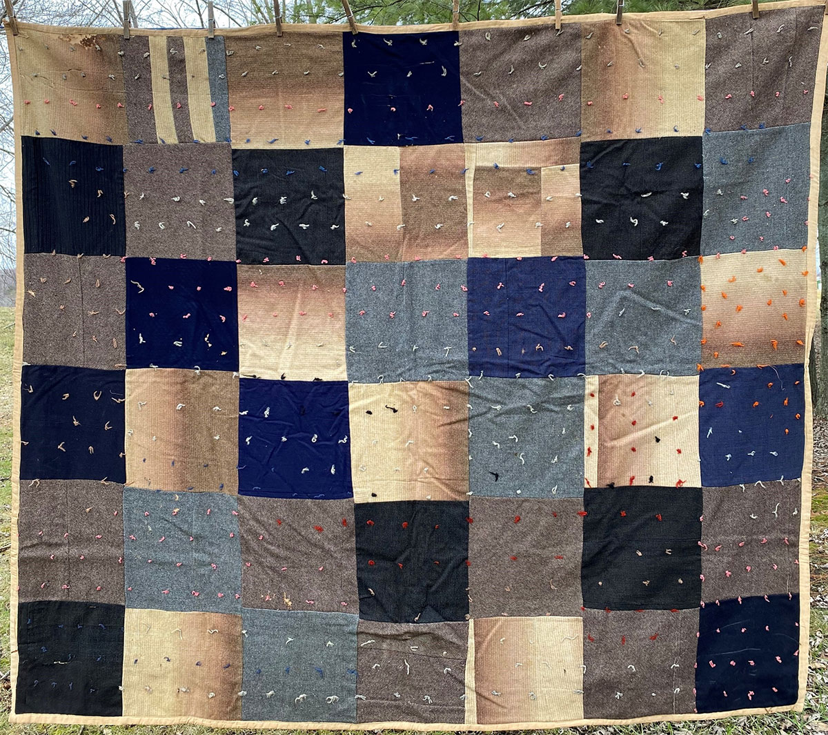 A quilt with a black, blue and beige square pattern.