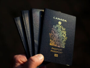 A hand holding four Canadian passports.