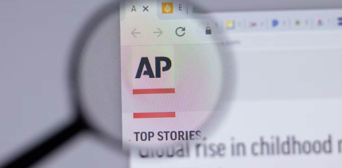A magnifying glass hovering over the AP logo on the Associated Press news website