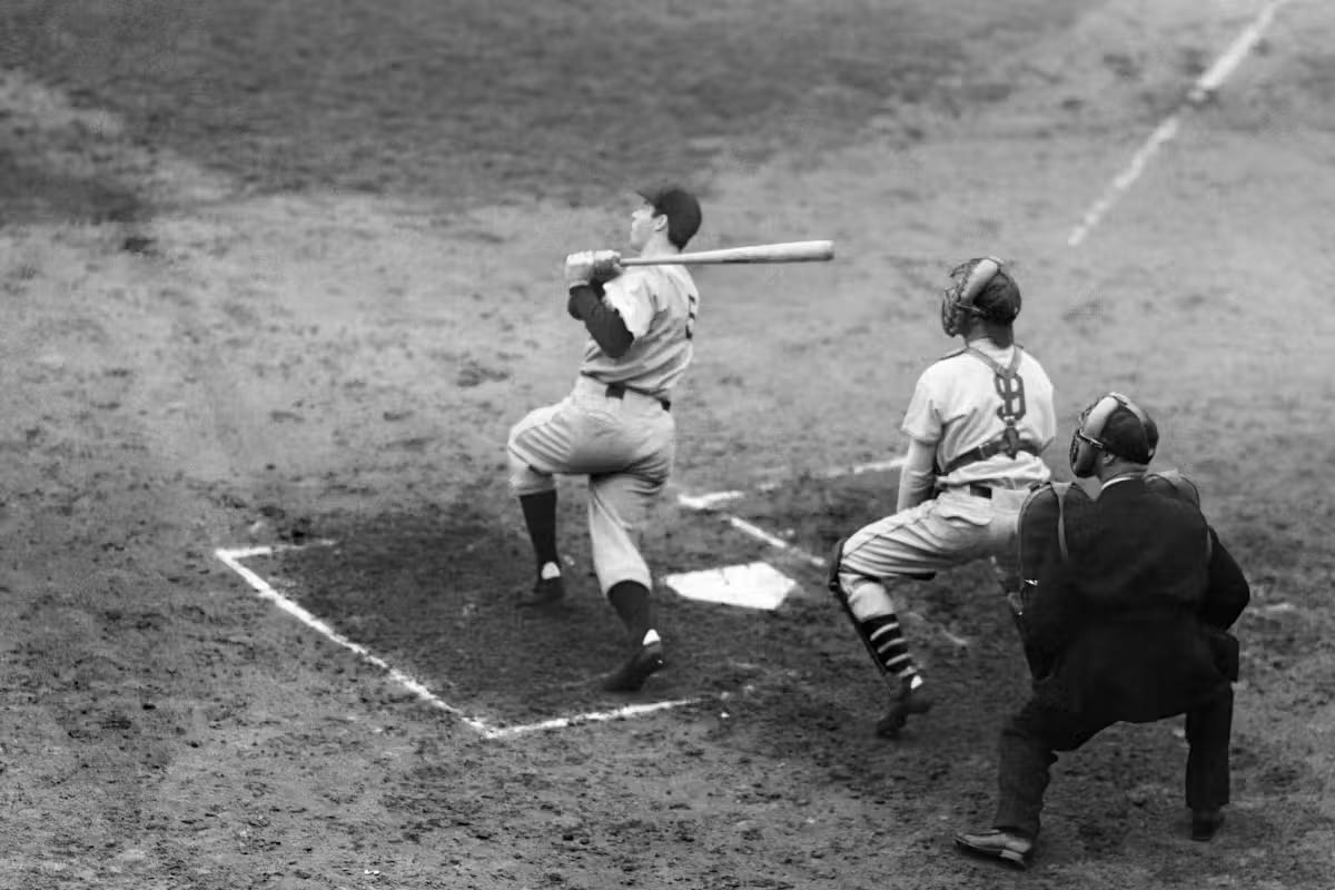 A black-and-white photo of a baseball player finishing a swing after hitting a pitch