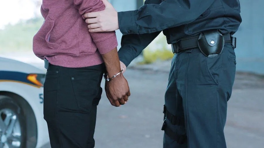 A police officer arrests a Black man.
