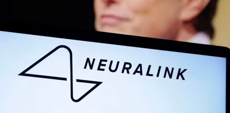 The Neuralink logo is displayed on a computer screen in front of a man's face in the background.