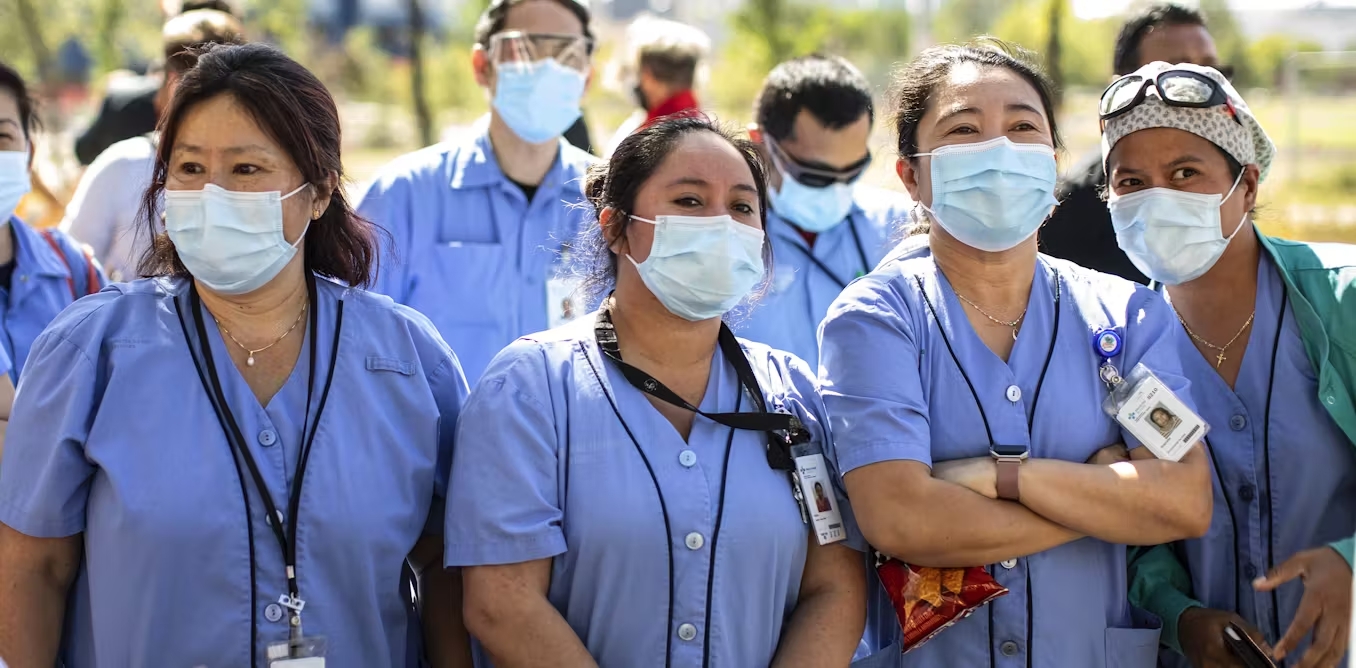 Women wearing scrubs and masks stand together