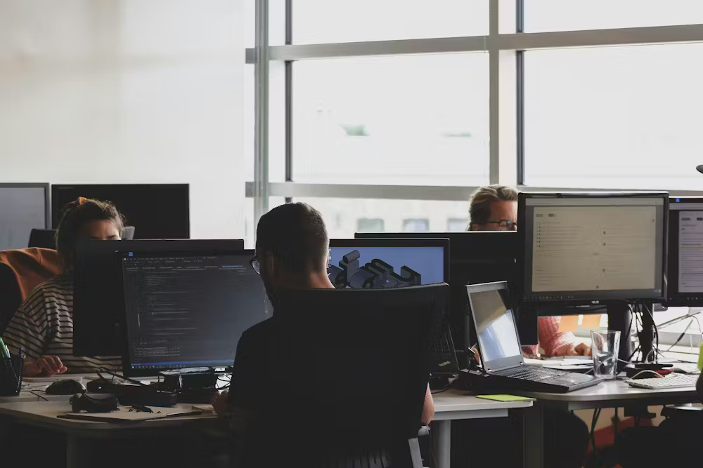 People in an office sit at desks working on computers