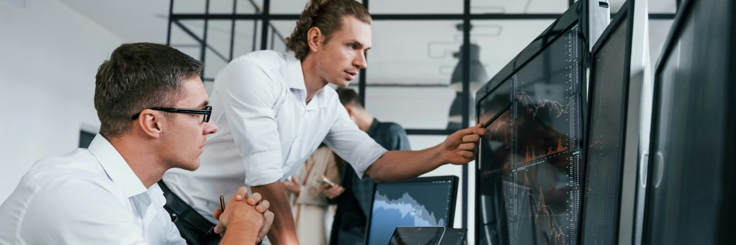 Two white men staring at a computer monitor and discussing what they see.