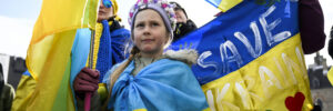 A young girl wrapped in a flag and holding another during a protest.